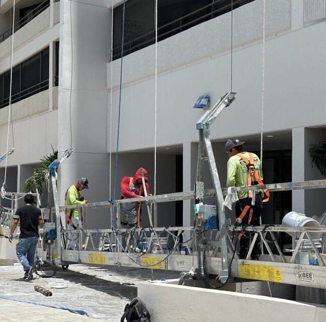 Painters on scaffolding repainting the exterior of the Ariel high-rise