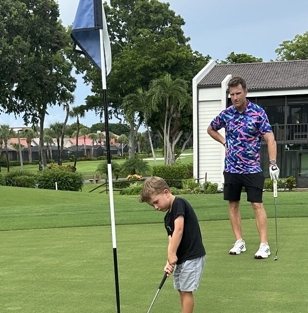 Young Bryce Camper putting on the green as his father watches