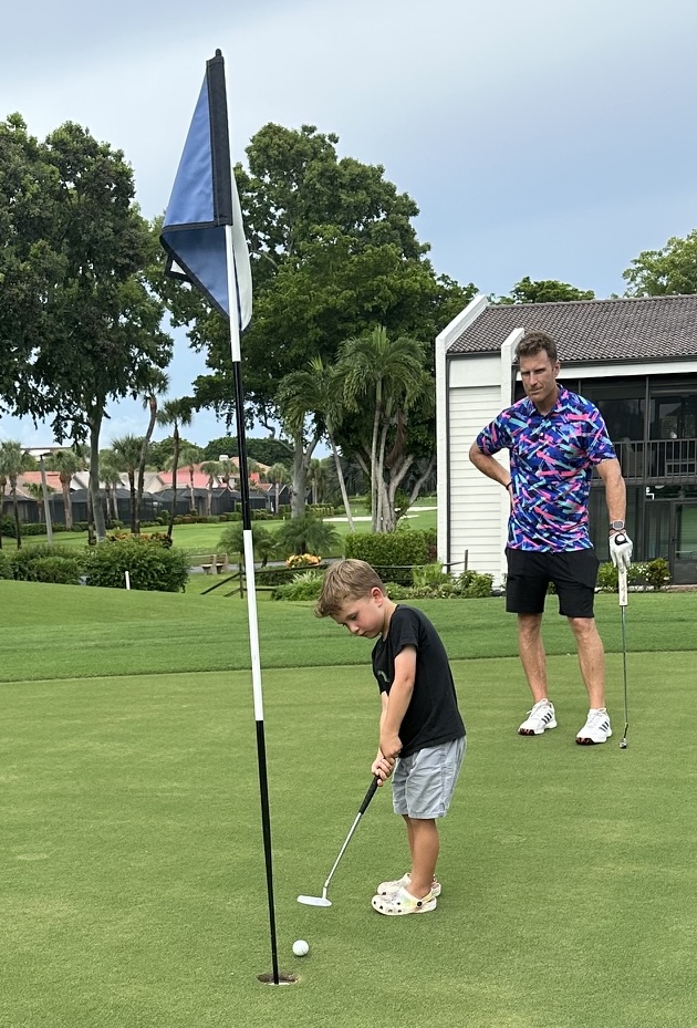 Young Bryce Camper putting on the green as his father watches